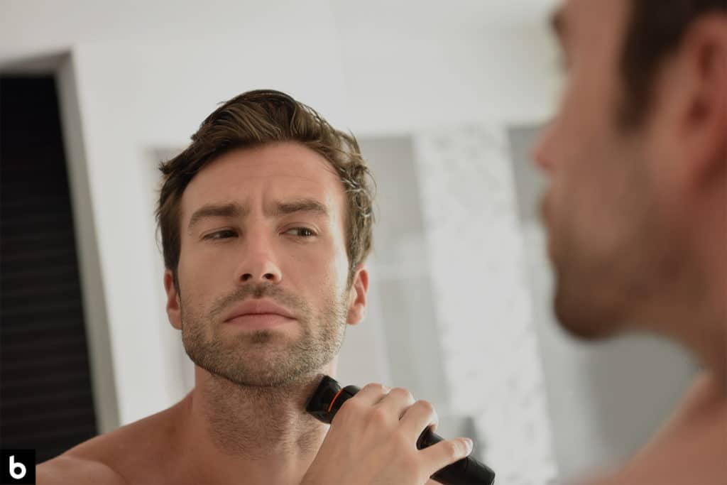 This is a photo of a man shaving facial scruff with an electric shaver.