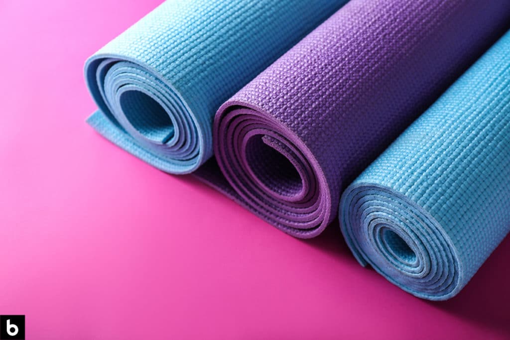 This is an image of 3 rolled up yoga mats on a pink background.