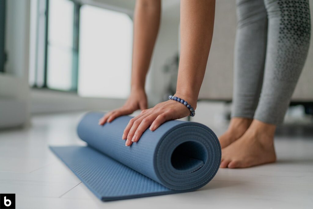 This is an image of a woman stretching with a yoga mat before a workout.