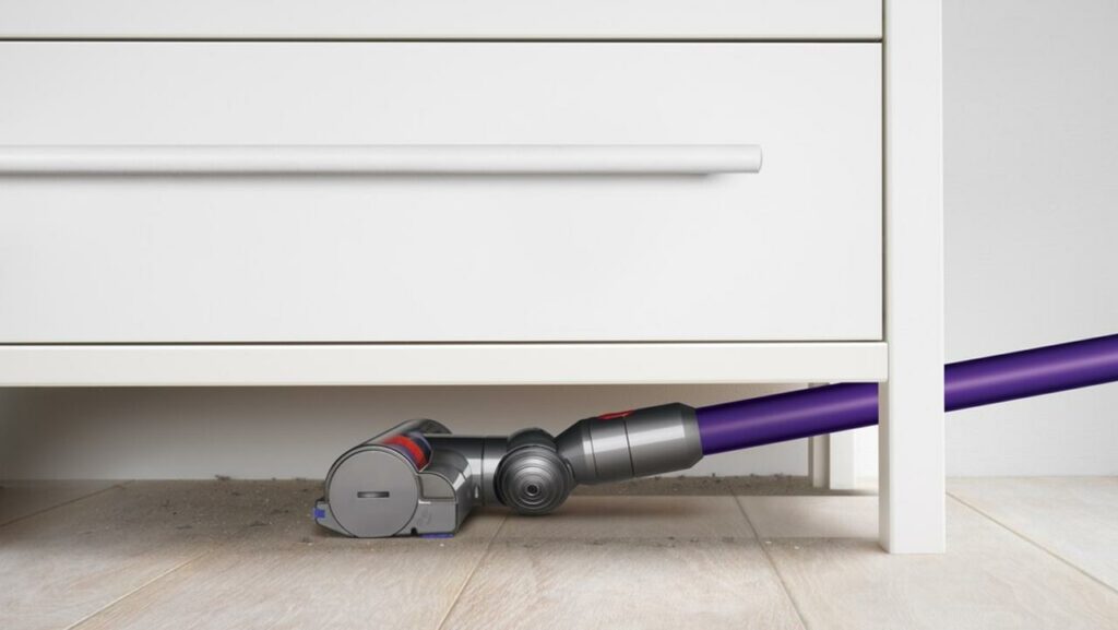 This is an image of a Dyson vacuum cleaner vacuuming under a storage shelf.