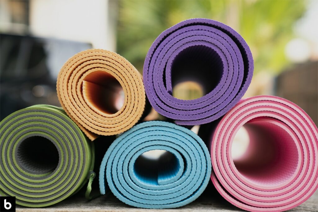 This is an image of 5 yoga mats of assorted colors stacked in a pile.