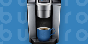 This is the cover photo for our Best Coffee Maker article. It features a metallic silver Keurig coffee maker overlaying a blue poster background with an embossed Burbro logo.