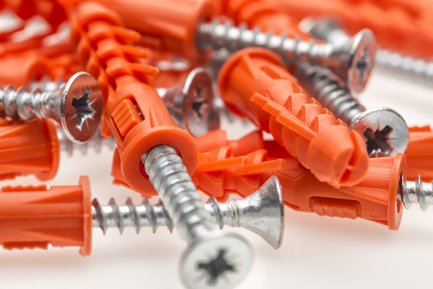 This is a cover photo for our Best Wall Anchors article. It features a pile of orange wall anchors with preset screws inserted.