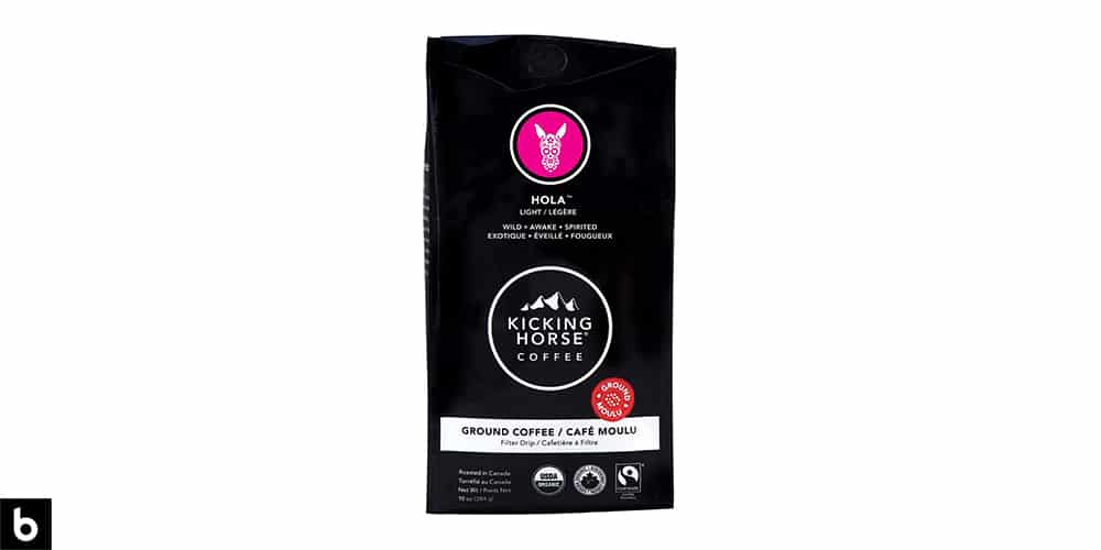 This is a product image, featuring a black and pink bag of Kicking Horse Coffee 'Hola' Light Roast coffee.