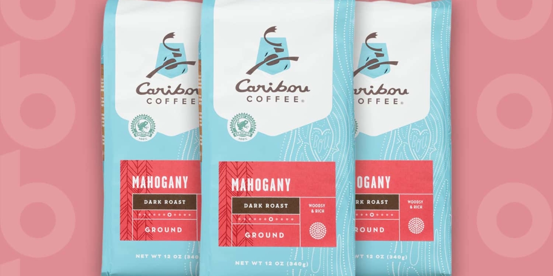 This is the cover photo for our Best Dark Roast Coffee article. It features 3 bags of Caribou Coffee Mahogany Dark Roast Coffee overlaid on a light pink background with embossed Burbro logo.