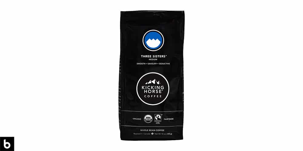 This is a product image of a black and blue bag of Kicking Horse 'Three Sisters' medium roast coffee.